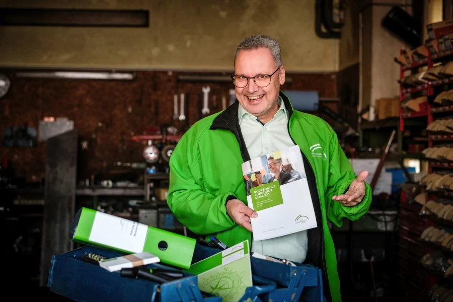 Arne Bär in einer Werkstatt vor einem offenen Werkzeugkoffer mit grünen Ordnern
